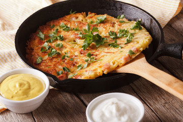 Potato rosti with herbs close-up in a pan on the table. Horizontal

