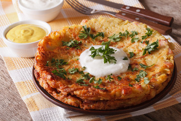 Rösti with sauce and parsley close-up on a plate on the table. horizontal
