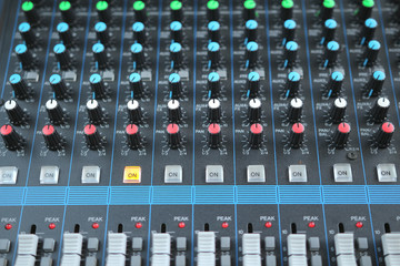 Close up of the rows of knobs and sliders on an analogue mixing