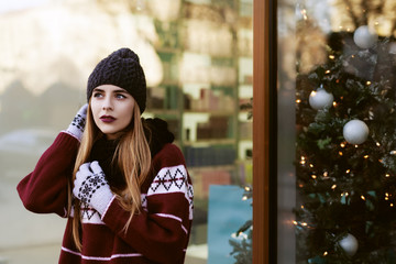 Street portrait of young beautiful woman with long blond hair wearing stylish winter clothes. Model looking aside. Female fashion concept