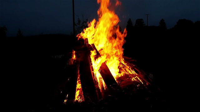 A bonfire in a dark area. A bonfire is a large but controlled outdoor fire used either for informal disposal of burnable waste material or as part of a celebration.