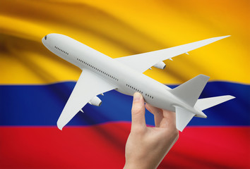 Naklejka premium Airplane in hand with flag on background - Colombia