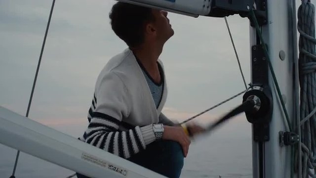 Man is working and raising sail on a boat in the sea. Shot on RED Cinema Camera.