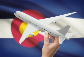 Airplane in hand with US state flag on background - Colorado