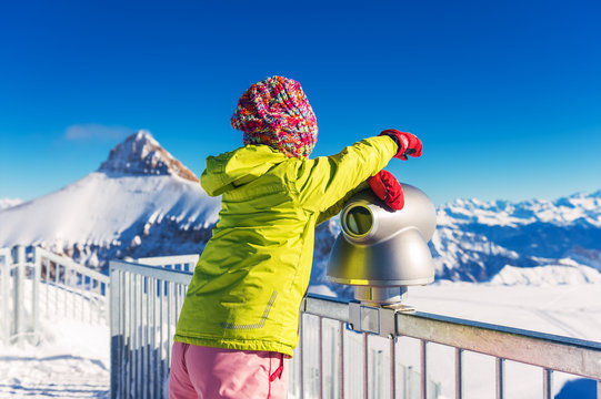 Little girl having fun during winter vacation in mountains, swiss Alps, back view