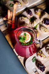 A carafe of fruity beverage with mint and lemon and wooden tray of appetizers at a banquet on a decorated tea table. Beautifully decorated table set  in the restaurant.