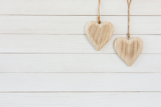 Two wooden hearts on white wooden background. Copy space