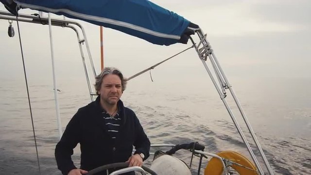 Senior man is driving a sailing boat in the sea. Shot on RED Cinema Camera.