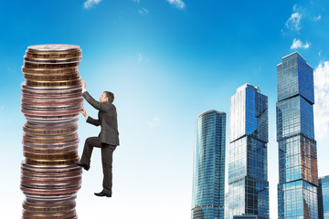 Businessman climbing up a huge stack of coins © cherezoff