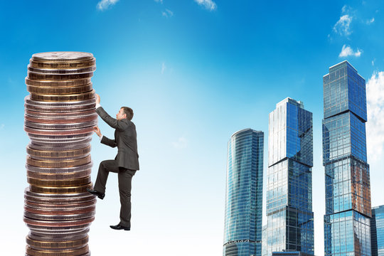 Businessman climbing up a huge stack of coins