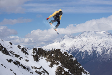 Flying snowboarder on mountains. Extreme sport.