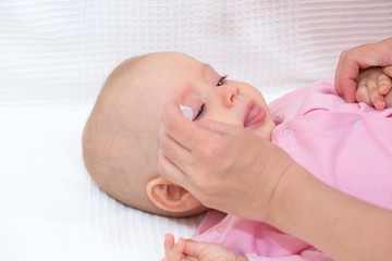 Mother cleaning baby's eyes isolated