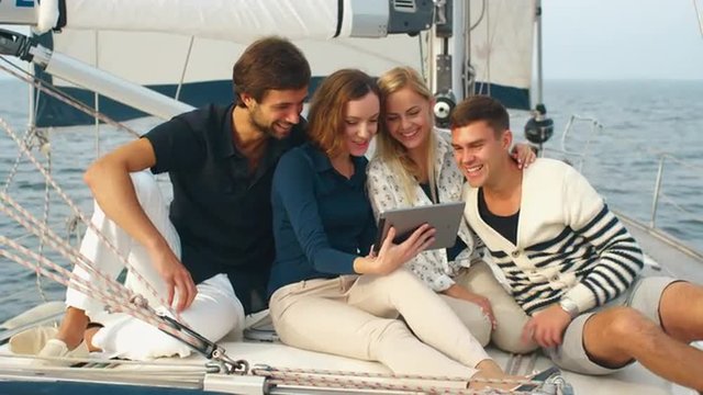 Group of people using tablet on a yacht in the sea. Shot on RED Cinema Camera.