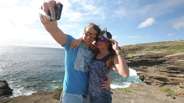 Couple tourists taking self portrait with camera phone on Hawaii, Oahu.
