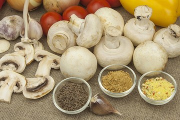 Raw mushrooms on a cutting board. Preparation of Champignons in the kitchen. Spices for food preparation. Vegetables to prepare meals.
