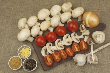Fototapeta na wymiar Raw mushrooms on a cutting board. Preparation of Champignons in the kitchen. Spices for food preparation. Vegetables to prepare meals. 