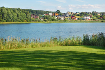 beautiful summer landscape with meadow, lake, forest and houses