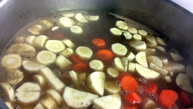 Pouring vegetables, carrots, swede and celery in a soup, at a restaurant kitc