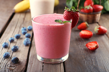 Glasses of fresh cold smoothie with fruit and berries, on wooden background