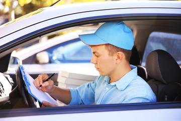Pizza delivery boy in car, close-up