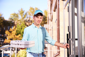 Pizza delivery boy holding boxes with pizza, outdoors