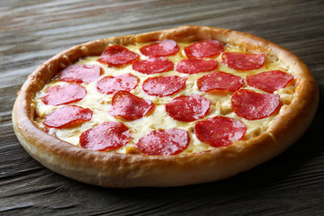 Tasty pizza with salami on wooden background