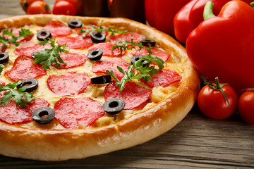 Tasty pizza with salami and red vegetables on wooden background, close up