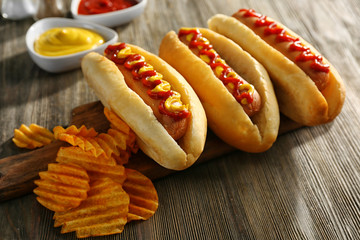 Tasty hot-dogs with chips on wooden background