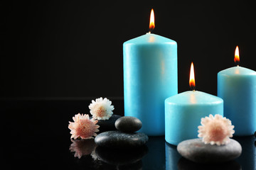 Spa composition of blue candles, flowers and stones on black background