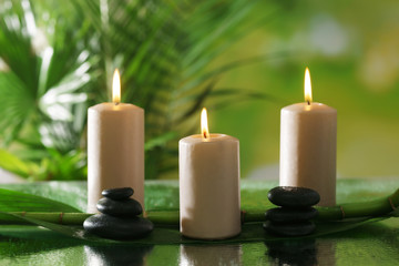 Fototapeta na wymiar Spa composition of candles, stones and bamboo on blurred background