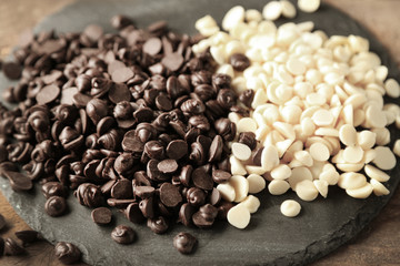 Chocolate morsels on board, on wooden background