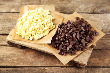 Chocolate morsels on board, on wooden background