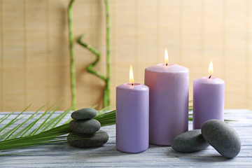 Obraz na płótnie Canvas Purple candles with spa stones and bamboo on table