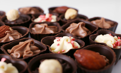 Delicious chocolate candies on white background, close up