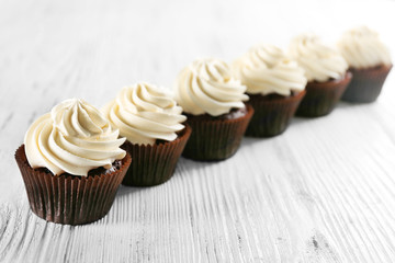 Tasty cupcakes on white wooden background, close up