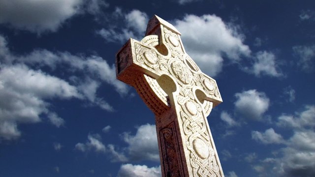 Large Celtic Cross with Time Lapse Clouds in the Background.