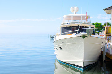 Big beautiful power yacht boat moored at a dock on a sunny calm day with the ocean in the background - 98928098