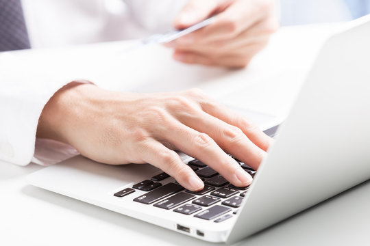 Man holding credit card in hand and entering security code using