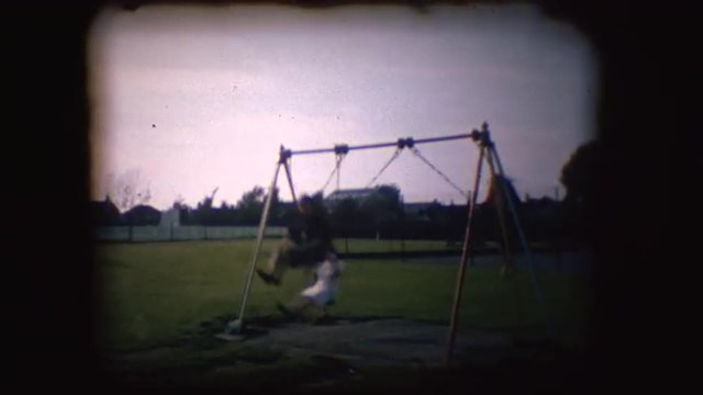 Vintage 8mm footage of children playing on a swing in England