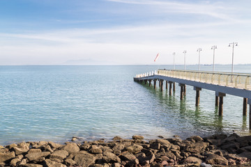 Jetty on the coast reaches out to calm blue sea