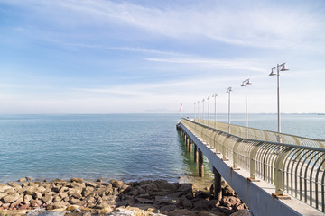 Obraz premium Jetty on the coast reaches out to calm blue sea