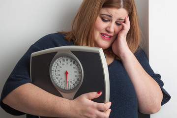 Worried woman holding a bathroom scale