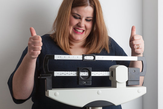 Woman celebrating weight loss on a medical weight scale