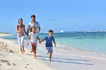 Family of four running on a sandy caribbean beach