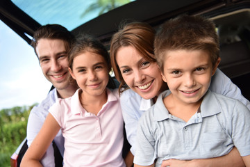 Family sitting in car trunk, ready for vacation