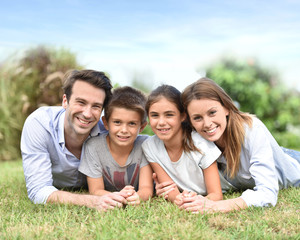 Fototapeta premium Portrait of happy family laying down in grass