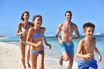 Family runnning on a sandy beach in Caribbean island