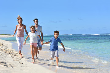 Family of four running on a sandy caribbean beach