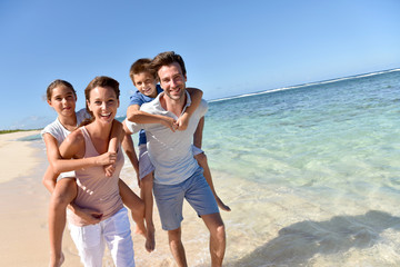 Parents giving piggyback ride to kids on a sandy beach