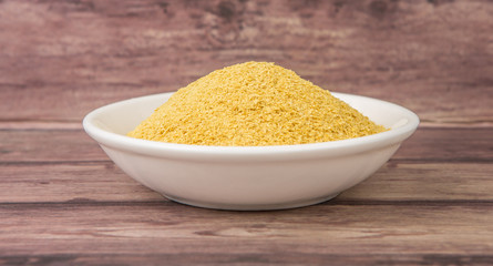 Dried bakers yeast in white bowl over wooden background